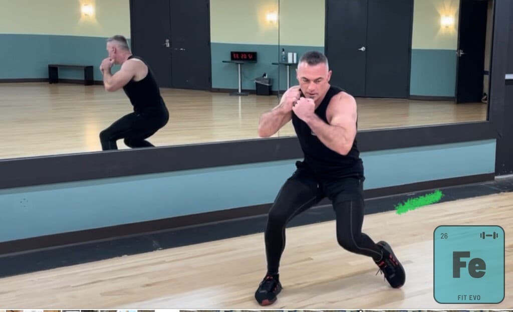 An instructor crouched in a boxing guard in the FIT EVO studio.