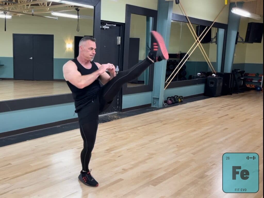 An instructor delivering a high side kick with guard raised.