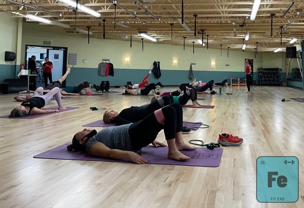 Members on mats performing glute bridges during a class.