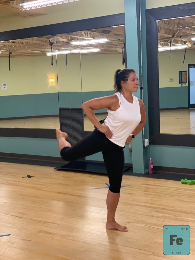 A member holding a standing balance and quad stretch in the studio.