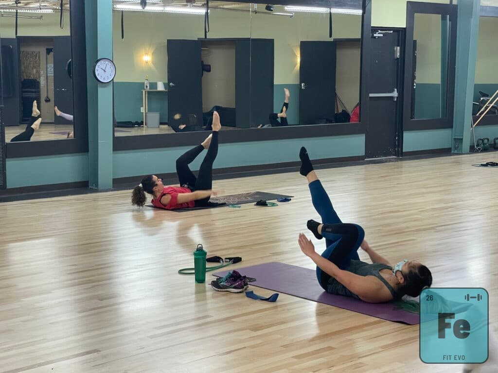 Members on mats performing leg raises during a class.