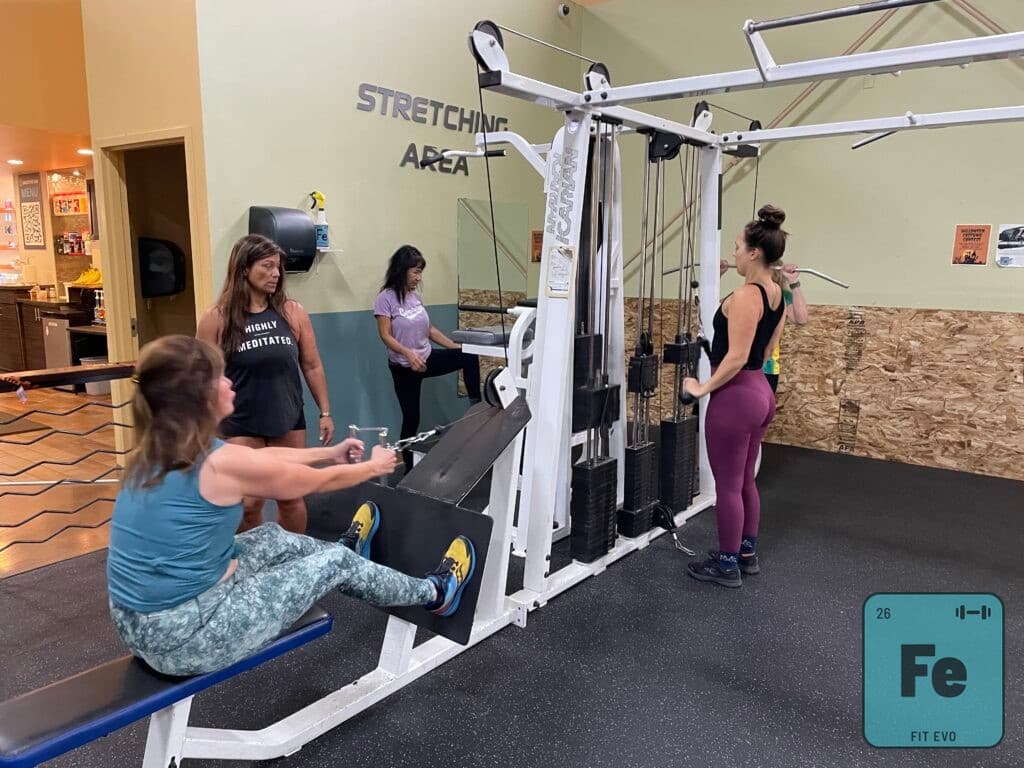 Members using the multi-station weight machine in the FIT EVO stretching area.