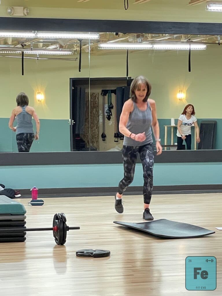 A member training on a balance board in front of the FIT EVO studio mirror.