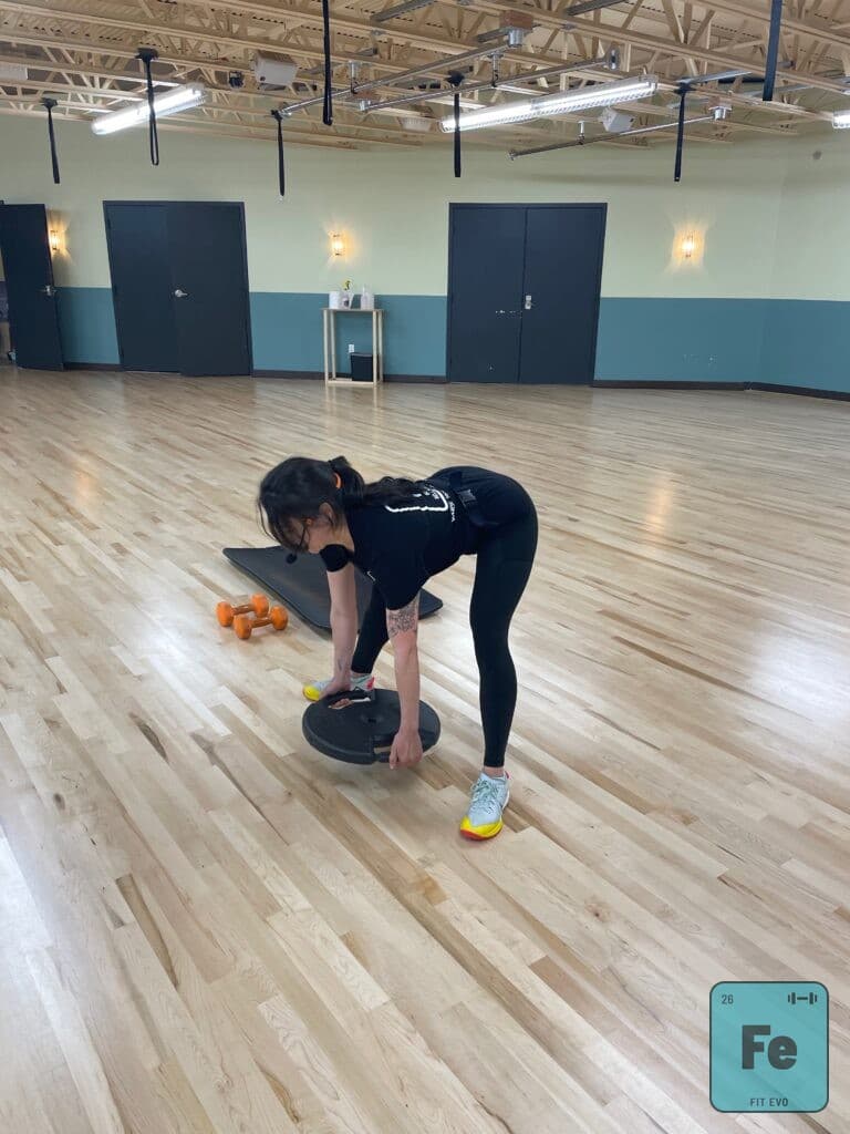 An instructor demonstrating a dumbbell lift in the FIT EVO studio.