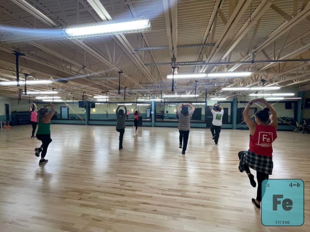 A dance fitness class mid-step in the FIT EVO studio.
