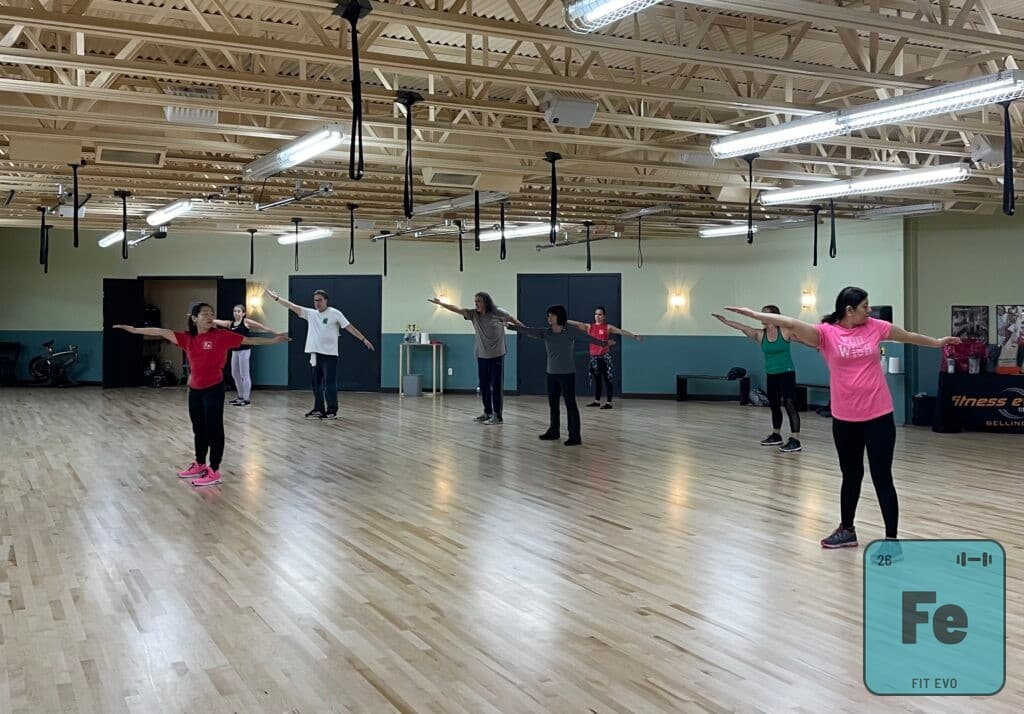 A class standing with arms extended sideways during a balance exercise.