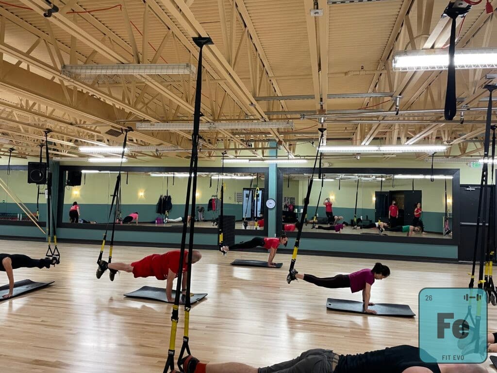 A TRX class holding plank positions with feet in the straps.