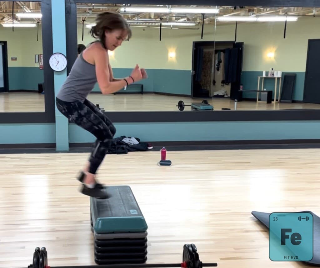 A member jumping onto a step platform during a class.