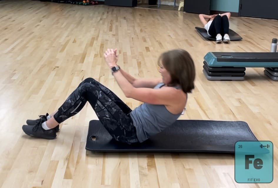 A member performing seated core work on a mat.