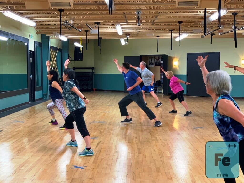 A dance fitness class moving through a step in the FIT EVO studio.