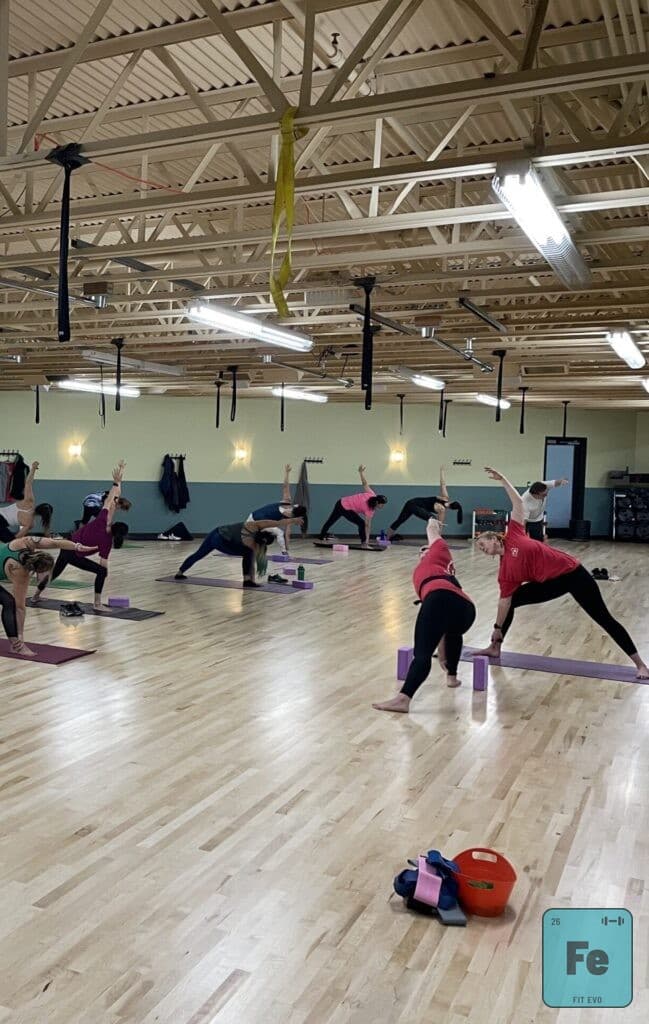 A yoga class holding a wide-legged triangle pose.