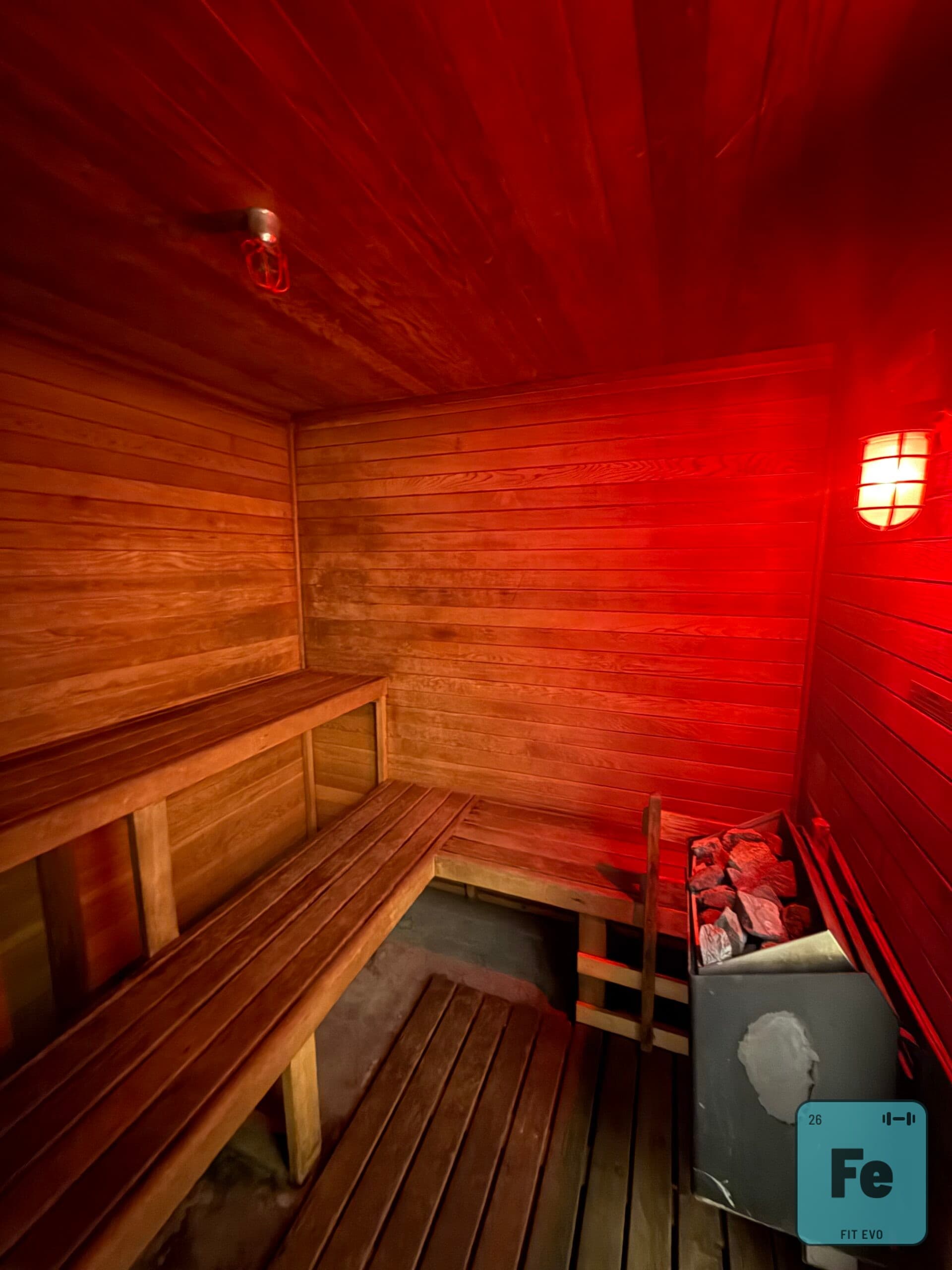 The cedar interior of the FIT EVO sauna, lit red.