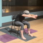 A participant reaching forward from a chair during a gentle chair class.